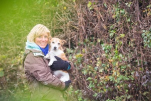portrait of Rosie Withey holding her jack russel dog, surrounded by greenery