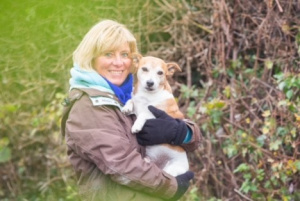 Rosie cuddling her Jack Russell Terrier, Alfie. Rosie is smiling towards the camera.