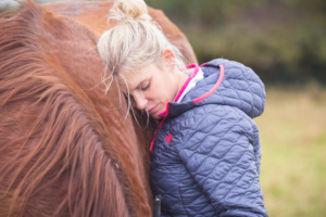 Workshop client, Lauren is resting her head on Jack's neck. Jack is Rosie's chestnut horse.
