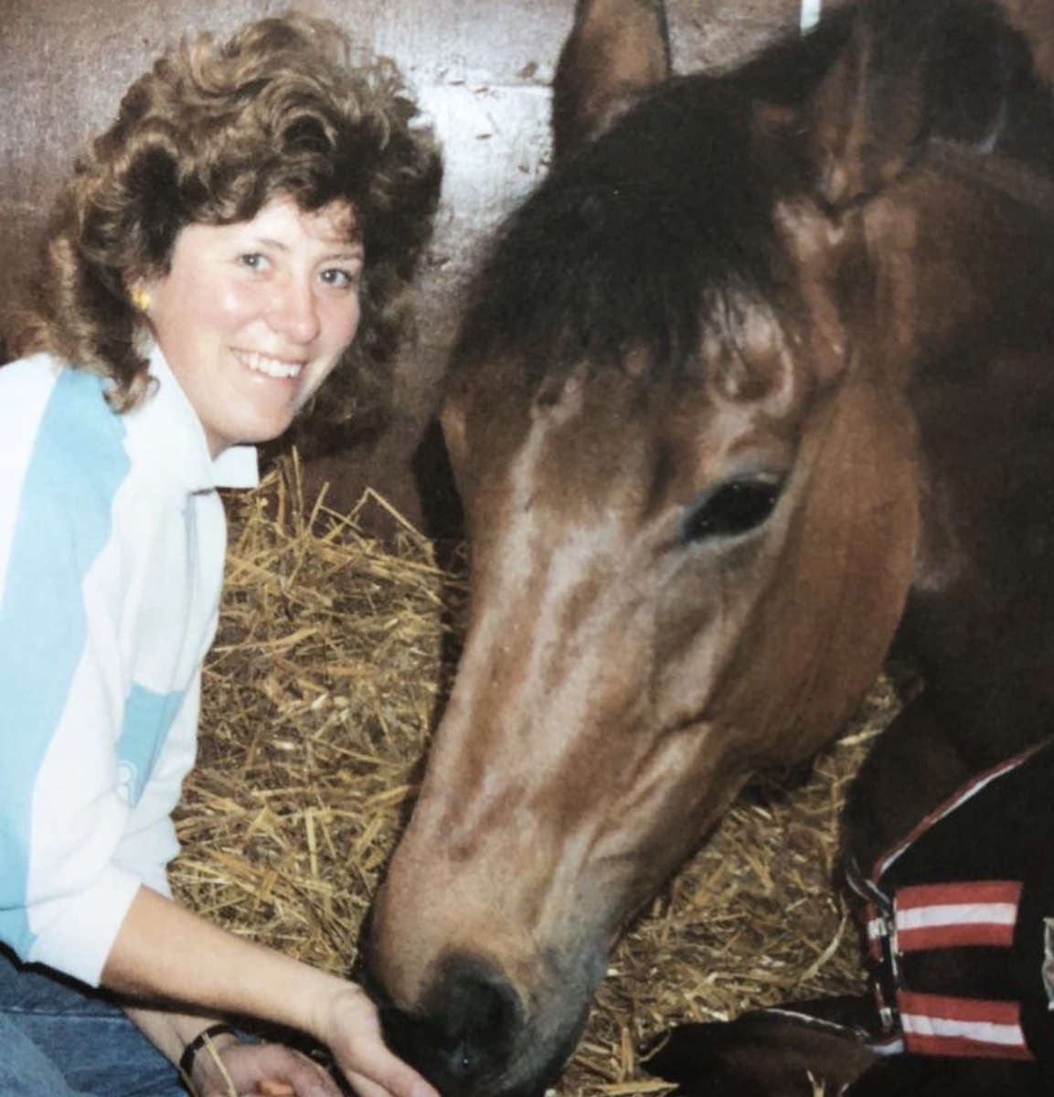 Rosie with Dusky's Spirit, the bay mare featured in this blog. The horse is resting in her stable and Rosie is feeding her and smiling for the camera.