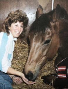 Rosie with Dusky's Spirit, the bay mare featured in this blog. The horse is resting in her stable and Rosie is feeding her and smiling for the camera.